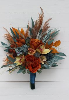 a bridal bouquet with orange flowers and green leaves on a white wooden wall background