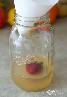 a mason jar filled with lemonade and strawberries on top of a kitchen counter