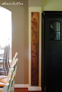 a tall wooden ruler sitting in the corner of a room next to a chair and cabinet