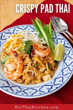 a white plate topped with shrimp and rice on top of a red table cloth next to silverware