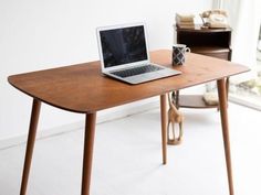 an open laptop computer sitting on top of a wooden desk next to a cup of coffee