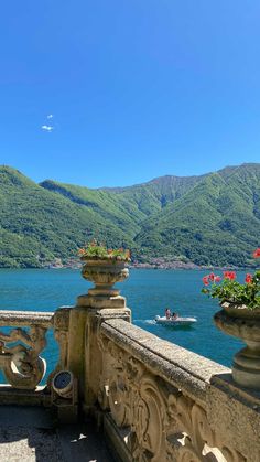 a balcony overlooking the water and mountains with flowers on it's balconies