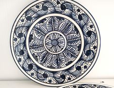 two blue and white plates sitting on top of a table next to each other,