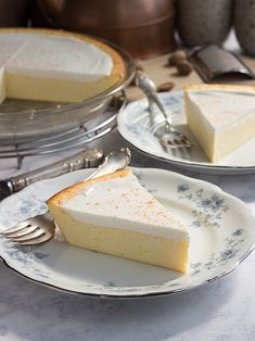 two plates with slices of cheesecake on them next to silverware and utensils