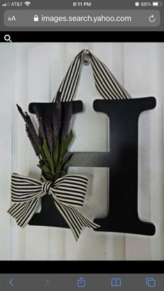 a black letter hanging on the side of a door with a bow and flowers in it