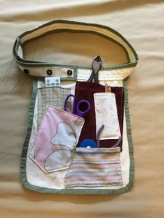 a handbag with various items in it sitting on a bed next to a pair of scissors