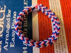 a red, white and blue braided bracelet sitting on top of an open book