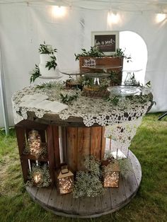 an outdoor table with candles and greenery on it in front of a white tent