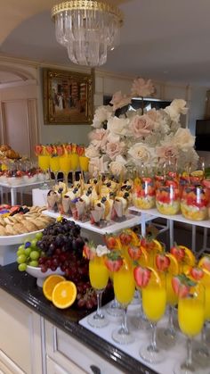 an assortment of fruits and pastries on display in a buffet style setting with chandelier hanging from the ceiling