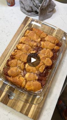 a glass dish filled with food sitting on top of a wooden cutting board next to a knife