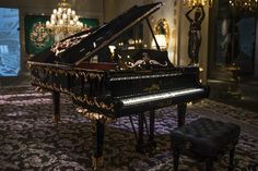 a grand piano sitting in the middle of a room with chandeliers and lights