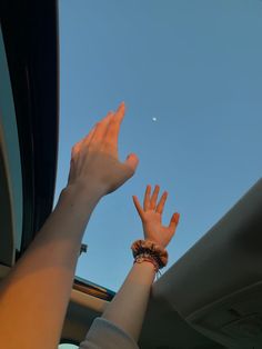 two hands reaching up into the air from inside a car