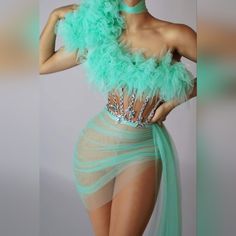 a woman in a green feathered dress posing for the camera with her hands on her hips