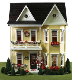 a doll house with lots of windows and balconies on the front, sitting in grass