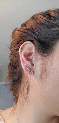 a woman's ear with three piercings on top of her head and one behind the ear