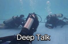 two scuba divers in the water with their gear on, and one is holding a camera