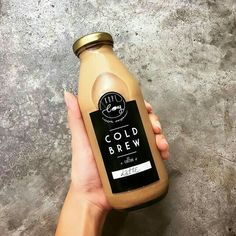 a hand holding a bottle of cold brew coffee on top of a gray countertop