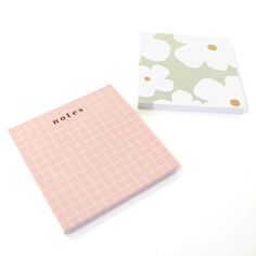 two notebooks sitting next to each other on top of a white table with flowers