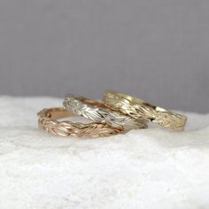 two gold and silver rings sitting on top of a white marble slab, with one ring in the middle