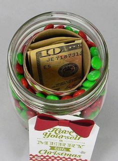 a jar filled with candy and money sitting on top of a table next to a card