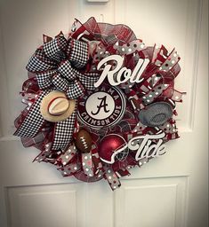 a football wreath on the front door decorated with red and white mesh, black and silver letters that read roll tide