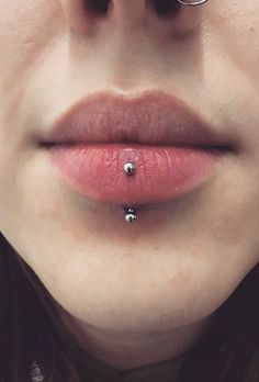 a woman's nose with piercings on it and two balls attached to the lip