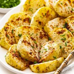 grilled potatoes on a white plate with parsley and seasoning next to it