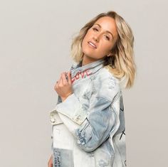 a woman wearing a jean jacket and jeans posing for the camera with her hands on her hips