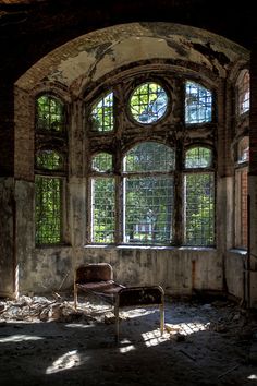 an abandoned room with two windows and a chair