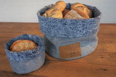 two blue baskets filled with bread on top of a wooden table next to each other