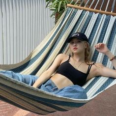 a woman laying in a hammock with her hat on