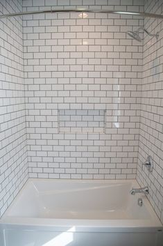 a white bath tub sitting inside of a bathroom next to a shower head faucet