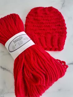 two red knitted hats sitting on top of a white marble counter next to each other