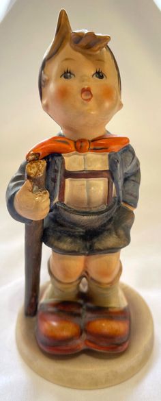 a ceramic figurine of a boy holding a hammer and wearing a red scarf