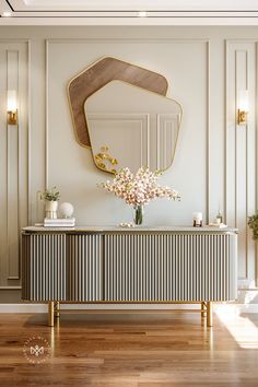 a white and gold console with flowers on it in front of a large wall mirror