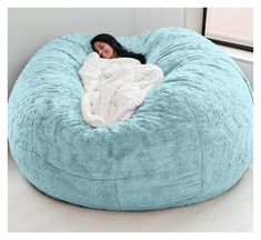 a woman laying in a large blue bean bag chair