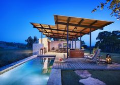 an outdoor living area with a pool and covered patio next to the swimming pool at night