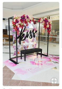 a bench in front of a display with flowers on it and the word bliss written below