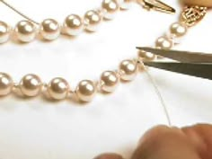 a pair of scissors cutting pearls on a white surface