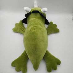 a green stuffed animal laying on top of a white table