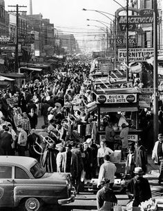 an old black and white photo of people on the street