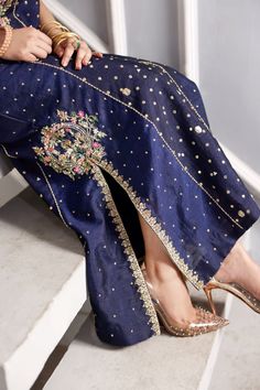 Take your look a notch up with this paneled A-lined long shirt infused with embroidered motifs on neckline and side slits embellished with nakshi, cut Dana, resham, crystal, stones and pearls beautifully crafted in navy blue raw silk. Paired with navy blue pants. Pakistani Clothes Online, Pakistani Designer Clothes, Embroidered Motifs, Embellished Shirt, Pakistani Wedding Dress, Handmade Flowers Fabric, Navy Blue Pants, Pants Fabric, Fancy Dress Design