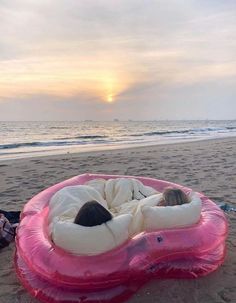 a person laying on an inflatable mattress at the beach