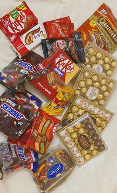 a pile of assorted candy and chocolates on a white sheet covered tablecloth