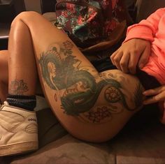 a person with tattoos on their legs sitting down