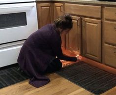 a woman kneeling down on the kitchen floor