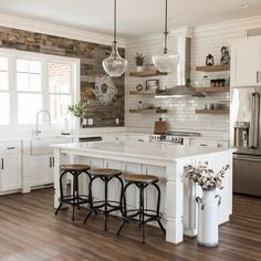 a kitchen with white cabinets and wooden floors, an island in the middle is surrounded by three stools