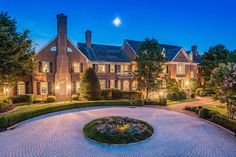 a large brick house surrounded by lush green trees and bushes at night with the moon in the sky