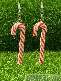 two candy canes dangling from silver earwires in front of some green grass