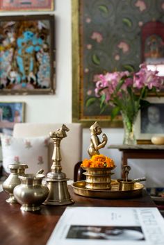 a table topped with brass vases filled with flowers and figurines on top of it